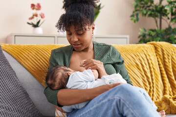 Mother and son sitting on sofa breastfeeding at home