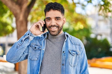 Young hispanic man smiling confident talking on the smartphone at park