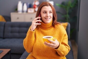 Young beautiful plus size woman talking on smartphone drinking coffee at home