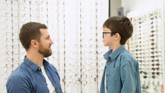 Little boy in optics store choosing glasses with his father. Ophthalmology concept