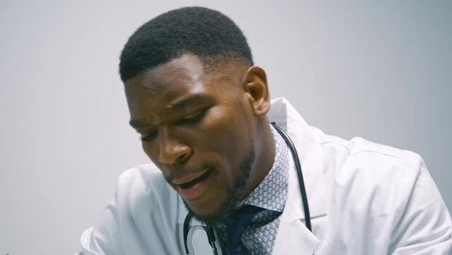Black Stock Footage of millennial Black man doctor smiling, working, and being productive at the hospital in his office at his desk