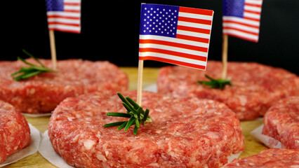 Round fresh raw mince beef burger cutlets with american flag and rosemary sprigs. - 568838408