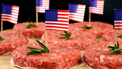 Round fresh raw mince beef burger cutlets with american flag and rosemary sprigs. - 568838425