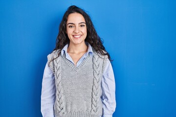 Obraz premium Young brunette woman standing over blue background with a happy and cool smile on face. lucky person.