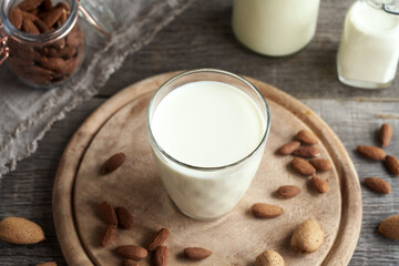 A glass of vegan almond milk with whole and shelled almonds
