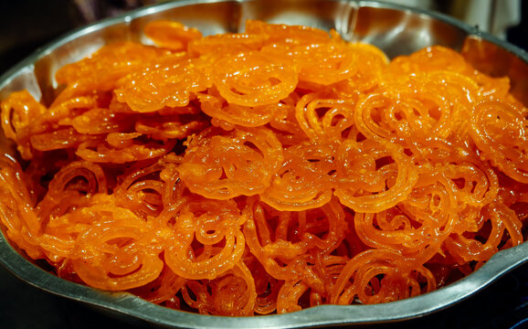 Jalebi, the most popular Indian sweet. Thin threads of dough, intricately intertwined, deep-fried until golden brown and poured with sugar syrup. Jalebi background
