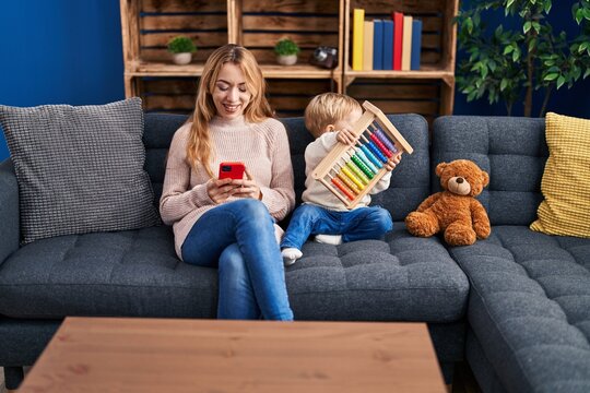 Mother and son using smartphone and playing with abacus at home
