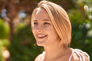 Naklejka premium Young blonde woman smiling confident looking to the side at park