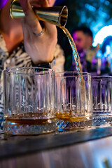 Bartender hand pouring whiskey on glass in bar