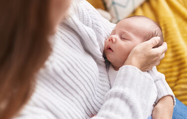 Mother and son sitting on sofa sleeping baby at home
