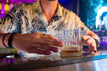 Bartender hand pouring whiskey on glass in bar