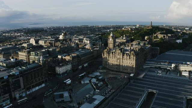Aerial view pulling away from Edinburgh during sunset with the train station in the foreground.