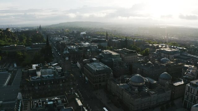 Drone shot of downtown Edinburgh, Scotland near sunset with a clock tower overlooking the neighborhood.