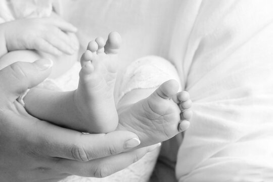 Baby feet in mother hands. Tiny newborn baby's feet on female hands closeup. Mom and her child. Happy Family concept. Beautiful conceptual image of parenthood