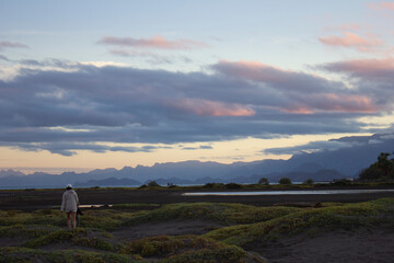 Girl walking in a beach at dusk with mountains in the background