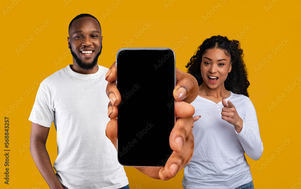 Poster black couple holding smartphone with blank screen and showing it at camera