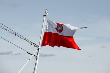 Waving Polish flag with a national emblem. © 9parusnikov