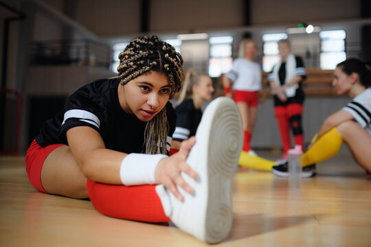 Group of multiaged women, sports team players. in gym stretching, warming up before match.
