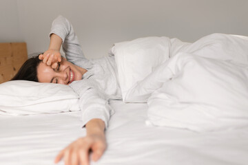 Cheerful caucasian millennial female sleeping on comfortable bed, enjoying softness, weekend