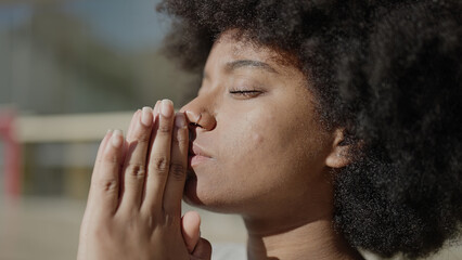 African american woman praying with closed eyes at street