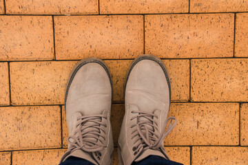 Gray women's shoes on feet and brown paving stones on background.