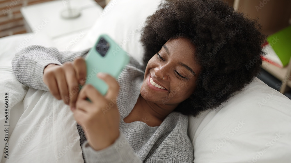 Sticker African american woman using smartphone lying on bed at bedroom