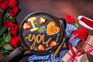 Cute Valentine pancakes, sweet homemade butter cake shaped in form of I love you, Be my heart inscription. Breakfast or gift idea for Saint Valentine day, with strawberry and syrup. roses bouquet