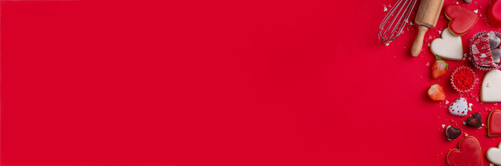 High-colored bright red Valentine day baking background, Various bakery ingredients, cookies, chocolates, sugar sprinkles, strawberry, rolling pin and whisk, for cooking valentine`s sweets, desserts