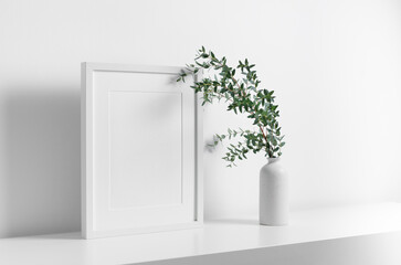 Portrait blank frame mockup in white room with eucalyptus plant decoration