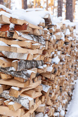 Stacked firewood covered with white snow, wood for kindling and heating. woodpile with stacked firewood birch tree covered fresh icy frozen snow and snowflakes. cold weather and snowy winter