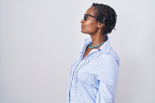 African woman with dreadlocks standing over white background wearing glasses looking to side, relax profile pose with natural face with confident smile.