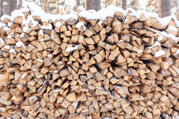 Stacked firewood covered with white snow, wood for kindling and heating. woodpile with stacked firewood birch tree covered fresh icy frozen snow and snowflakes. cold weather and snowy winter