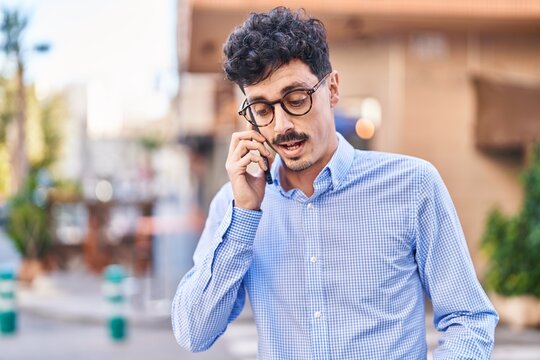 Young caucasian man talking on the smartphone with serious expression at street