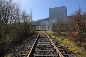 Würgassen, Germany - 03/23/2020: Old train tracks run towards a massive metal gate. There are...