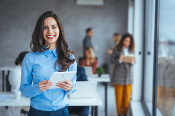 Waist up portrait modern business woman in the office with copy space. Female executive wearing businesswear standing outside modern meeting room and checking data on tablet.