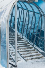 Blue glass covered elevated pedestrian crossing in winter  in snow