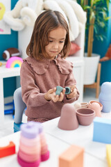 Adorable hispanic girl playing with toys standing at kindergarten
