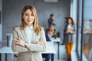 Successful businesswoman standing in creative office and looking at camera. Young woman...