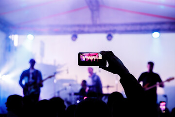 Fototapeta na wymiar People on the dance floor are shooting a concert on a mobile phone.