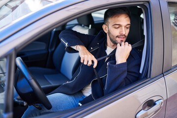 Young hispanic man smiling confident wearing car belt at street