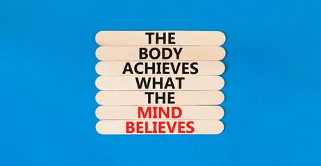Mind and body symbol. Concept words The body achieves what the mind believes on wooden stick. Beautiful blue table blue background. Copy space. Motivational mind and body concept. © Dzmitry