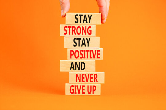 Never give up symbol. Concept words Stay strong stay positive never give up on wooden blocks. Beautiful orange background. Copy space. Businessman hand. Motivational business never give up concept.