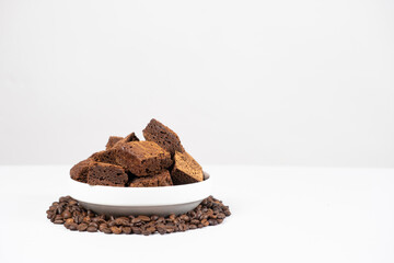 Chocolate cake sliced into squares in a white plate, brownie and coffee beans, space for text