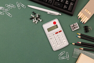 stationery items around of image on green background. Back to school background, banner with copy space. Student's or engineer's supplies. Office objects on dark green background. Calculator, keyboard - 568851822