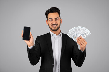 Online Profit. Smiling Arab Businessman Showing Blank Smartphone And Holding Dollar Cash