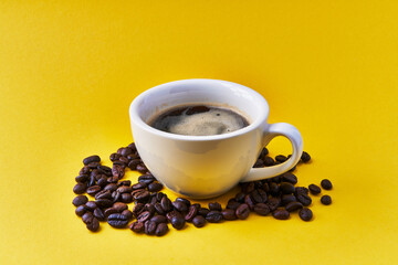  One cup of espresso and coffee beans over yellow background