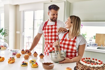 Young couple smiling confident cooking chocolate cake at kitchen