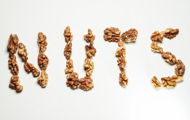 Nuts word made from a lot of nut fruits against white background. Concept image for nuts as a healthy snack during the day or breakfast.
