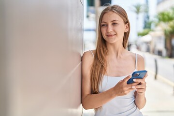 Fototapeta na wymiar Young caucasian woman smiling confident using smartphone at street