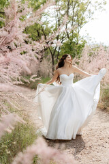 a young girl bride in a white dress is spinning on a path
